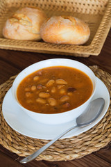 Bean soup with the buns on a  wooden table.