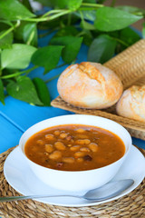 Bean soup with the buns on a blue wooden table.