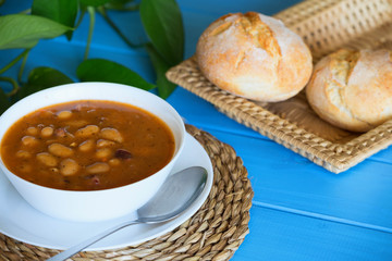 Bean soup with the buns on a blue wooden table.