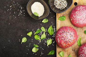 Pink buns for the vegetable Burger on the basis of beet with sesame seeds on dark background. Top view