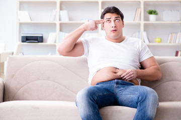 Fototapeta premium Man suffering from extra weight in diet concept