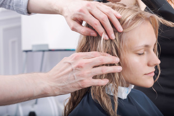 A hands of hairdresser making a haircut for a blonde girl