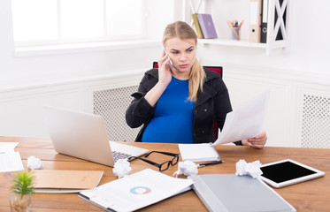 Pregnant business lady at work reading papers