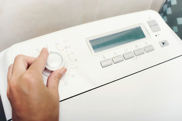 Close Up of woman's hand choosing cycle crogram on washing machine