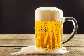 Pouring beer into a glass on a wooden table. Alcoholic beverages. Alcohol-free beer. Sale of beer to the bar.