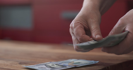 side shot of woman counting dollars on wood table