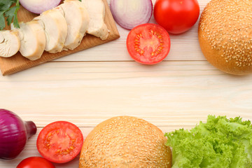 Hamburger Building Kit. round sandwich bun with, tomato, red onion, green lettuce, grilled chicken fillet on white wooden background. Top view with copy space.