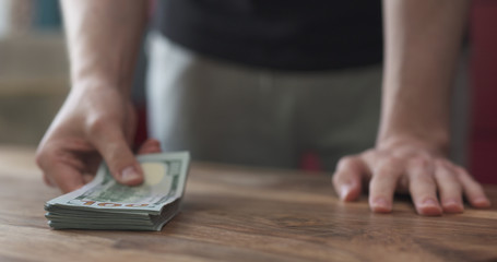 front shot of man counting dollars on wood table