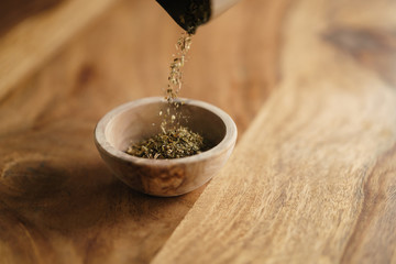 dried provence herb mix falling in wood bowl for seasoning on table