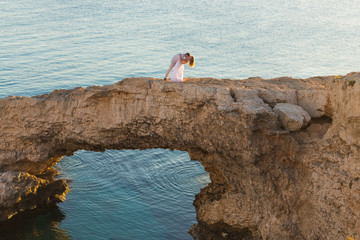 beautiful gorgeous bride and stylish groom on rocks, on the background of a sea, wedding ceremony on cyprus
