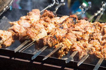 Grilled kebab cooking on metal skewer. Roasted meat cooked at barbecue.Traditional eastern dish, shish kebab. Grill on charcoal and flame, picnic, street food