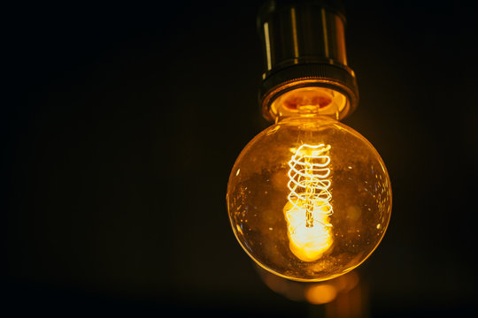 single light bulb on dark background with space for text.