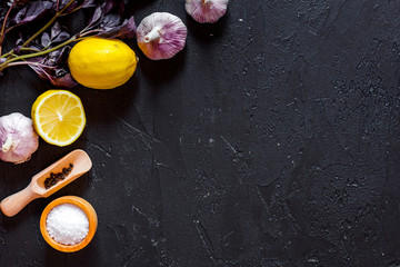 Obraz na płótnie Canvas Cook workplace. Lemon, garlic, basil on black table background top view copyspace
