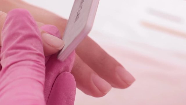 Professional manicure on fingers of the client closeup footage. Master of the nail service giving shape to the nails. Spa, beauty industry, relax concept.