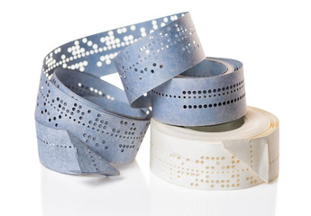 white and blue perforated punched tapes with old data  is isolated on background, close up
