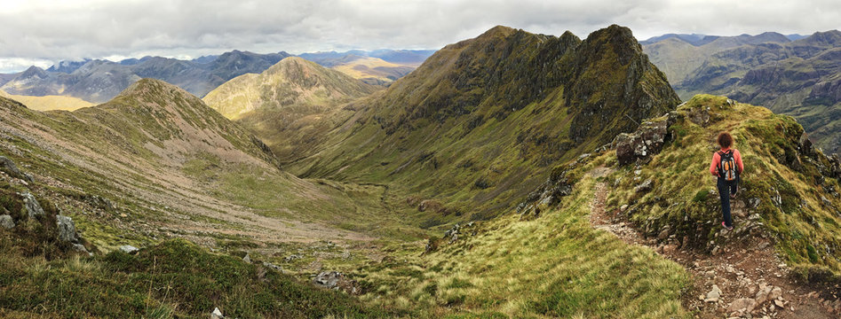 Woman admiring the notorious Aonach Eagach ridge in the Scottish Highland. Glencoe, Scotland, UK