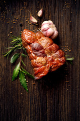 Smoked ham on a wooden rustic table with addition of fresh aromatic herbs and spices, natural product from organic farm, produced by traditional methods, top view