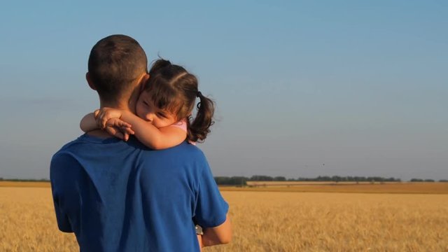 The daughter embraces his father. Father and daughter in a field of wheat