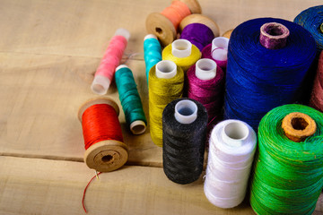 Coils with threads of different colors on a wooden table