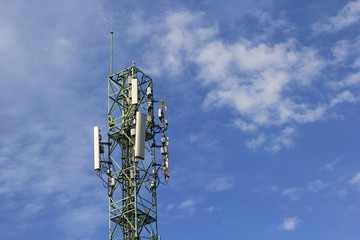  Mobile phone and communications tower with cloud and blue sky.