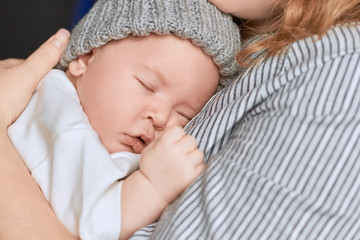 Woman holding a sleeping baby. Little kid with closed eyes. Mother and child.