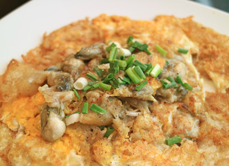 Close-up of fried oysters with crispy omelette topped with chopped spring onion 