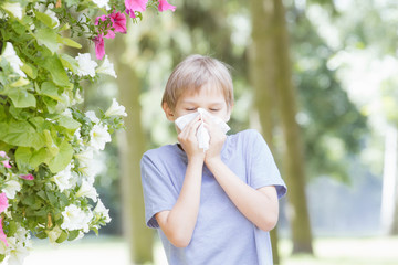 Allergy. Kid is blowing nose with tissue paper at the park