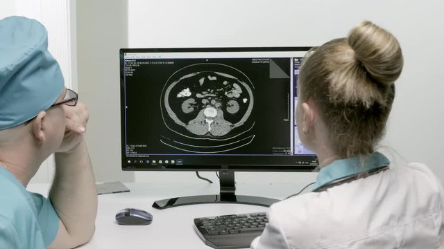 The doctors discuss the pictures of the patient looking into the computer monitor.