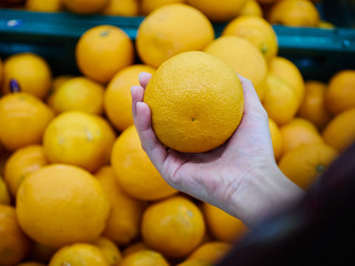 Girl hand holding orange for shopping in store