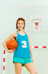 Teenage basketball player with ball under her arm