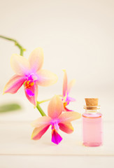Fototapeta na wymiar Essence of orchid flowers on table in beautiful glass jar