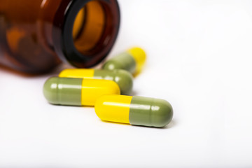 Colorful pills spilling out of a toppled bright red orange pill bottle