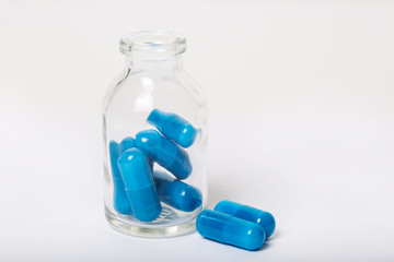 Blue pills in pill bottle on white background