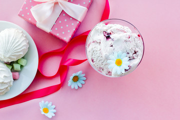 berry ice cream in glass dessert bowl on blurred background with gifts, sweets, pink background, selective focus, blur