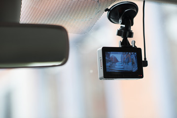 A car dash cam mounted on the front windshield recording the traffic ahead in case of an emergency situation or an accident