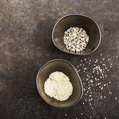 Sesame black, brown and white in dark ceramic bowls on a dark background. Top View