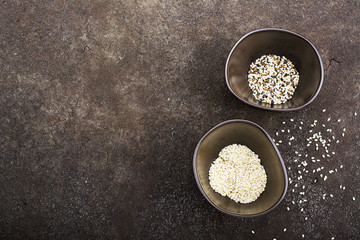Sesame black, brown and white in dark ceramic bowls on a dark background. Top View