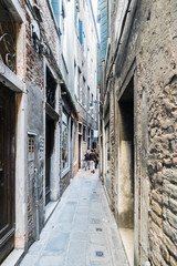 Fototapeta na wymiar Narrow cobblestone alley in the oldest part of Venice, called 