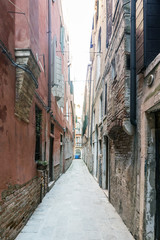 Fototapeta na wymiar Lonely cobblestone alley in the oldest part of Venice in Italy