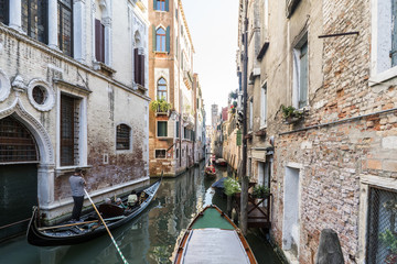 Fototapeta na wymiar Facades of houses on a narrow canal with gondolas passing in Venice, Italy