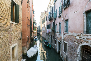 Fototapeta na wymiar Facades of houses on a narrow canal with clothes lying in Venice, Italy