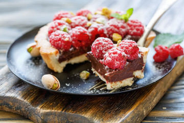 Mini tart with fresh raspberries and a fork.