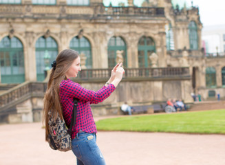 Young woman with long hair use smartphone in european old city