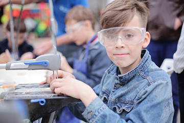 Young boy working with fret saw. Classes for young carpenter cutting wooden board form using...