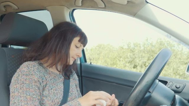 Young woman takes medicine, pill sitting at the wheel of the car.