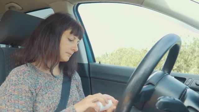 Young woman takes medicine, pill sitting at the wheel of the car.