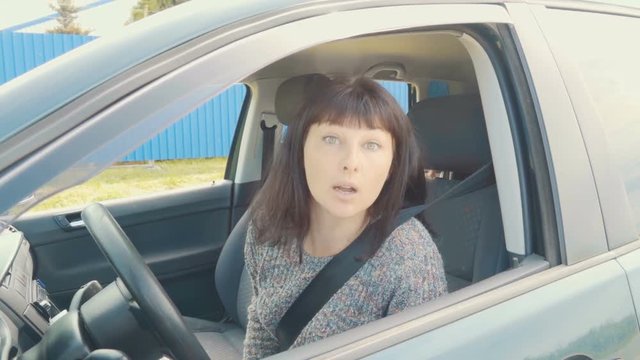Young angry woman in perplexity sitting in the car.