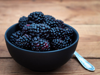 Blackberries in black bowl on wooden background