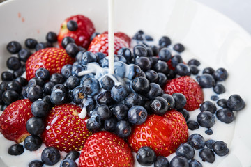 Strawberries, blueberries and milk in a white bowl