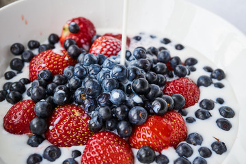 Strawberries, blueberries and milk in a white bowl